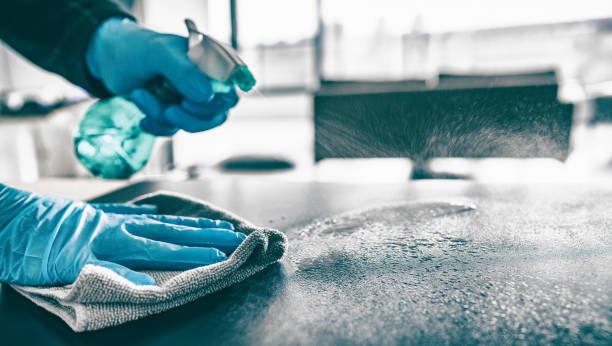 Cleaner spraying and wiping a desk